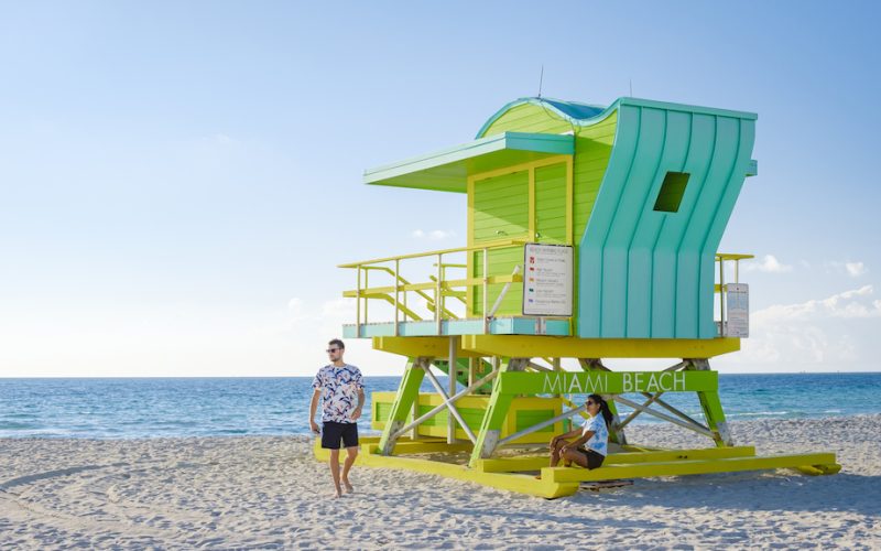 Miami Beach, a couple on the beach at Miami Florida, lifeguard hut Miami Asian women and caucasian men on the beach during sunset. man and woman watching sunrise